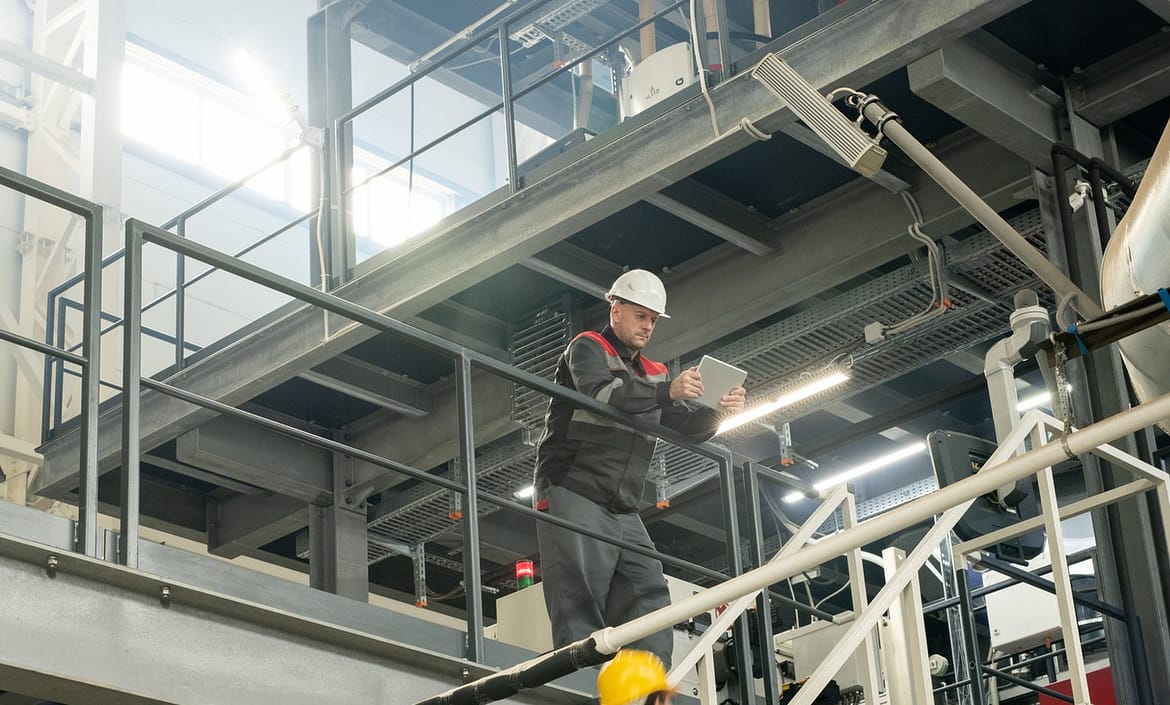 Foreman with tablet bending over staircase where female worker moving upwards